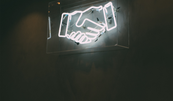 serveneeds Neon handshake sign symbolizing VMRS commitment to serving your needs.